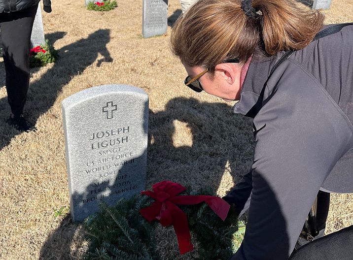person laying a wreath on a grave